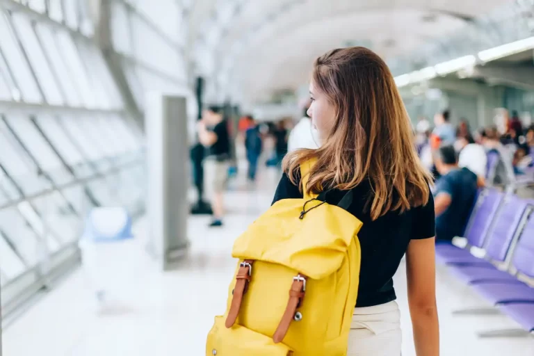 Young woman with a yellow backpack in an airport with a Spain Study Visa